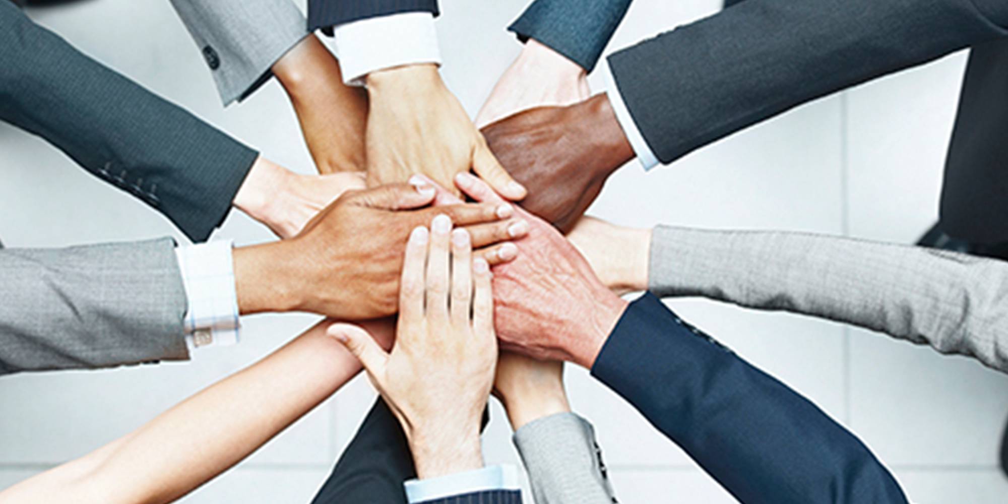 A group of business people putting their hands together in a circle.